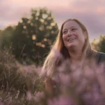 Vrouw tussen de paarse heide onzekerheid en toch stralen, natuurlijk licht fotografie Eveline, Schoonhoven